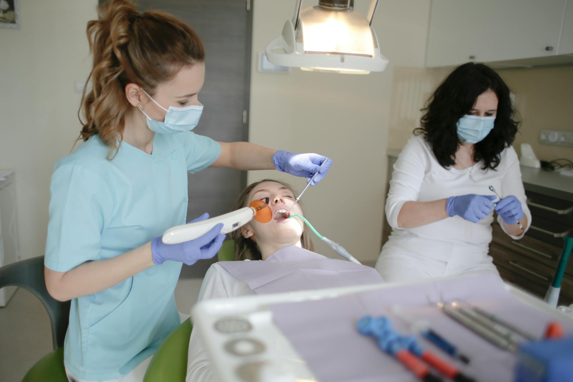 woman in light blue scrub suit holding dental curing light