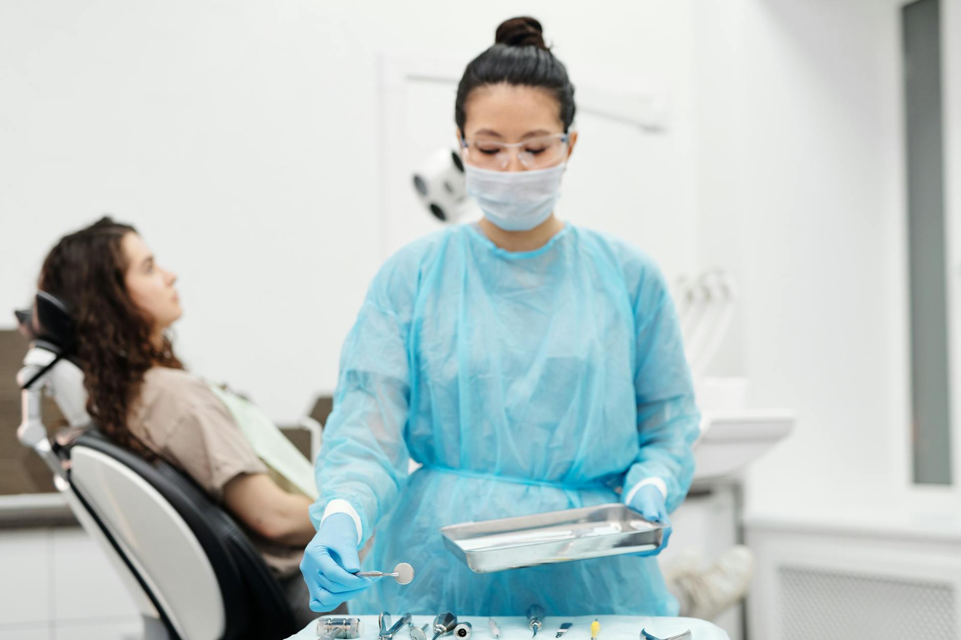 a woman in scrub suit holding stainless steel dental tools